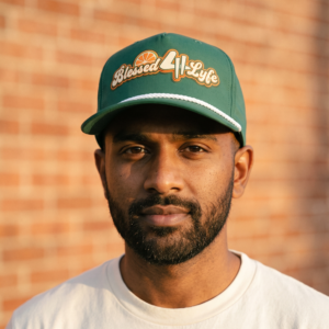 Man wearing green Blessed 4 Lyfe rope cap against brick wall