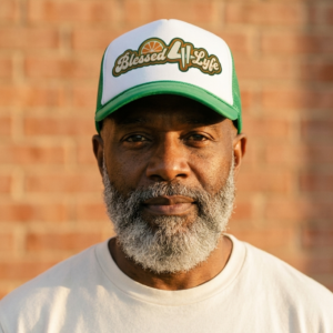 Man wearing green Blessed 4 Lyfe trucker hat against brick wall